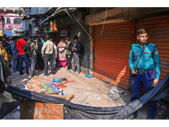 A police personnel stands guard near the rubble that fell from a damaged building following an earthquake in Old Dhaka on November 21, 2025. (Photo by Munir UZ ZAMAN / AFP)