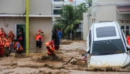 Rescuers wade through flood waters by holding a rope in their effort to evacuate residents who are trapped at their houses in Padang, West Sumatra province on November 27, 2025. (Photo by Rezan Soleh / AFP)
