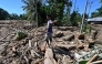 A man walks across mud and debris in a flood affected area in Meureudu, Pidie Jaya district in Indonesia's Aceh province on November 30, 2025. (Photo by Chaideer Mahyuddin / AFP)