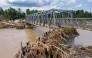 Aerial photo shows residents climbing debris to cross the river on a newly built bridge connecting Aceh and North Sumatra province on December 9, 2025. (Photo by Chaideer Mahyuddin / AFP)