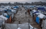 Men walk along a muddy alley at a makeshift camp sheltering displaced Palestinians after heavy rains in the Zeitoun neighbourhood of Gaza City on December 11, 2025. (Photo by Omar AL-QATTAA / AFP)