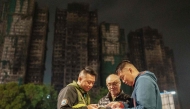 This picture taken on December 10, 2025 shows Yip Ka-kui (C) and his sons Yip Shun-ting (L) and Yip Shun-yin (R) looking at old photographs of his wife Pak Shui-lin. (Photo by Yan Zhao / AFP)