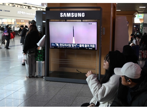 People sit in front of a television screen showing a news broadcast with file footage of a North Korean missile test, at a train station in Seoul on January 4, 2026. Photo by Jung Yeon-je / AFP