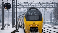 A train moves along a platform covered in snow, at Arnhem Central Station, as train service is resuming after an IT outage at the Dutch national railway service Nederlandse Spoorwegen (NS), on January 6, 2026. (Photo by Robin van Lonkhuijsen / ANP / AFP)