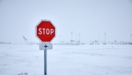 This photograph shows a stop sign near runways as snow blankets the tarmac, causing flight cancellations at Orly Airport, south of Paris on January 7, 2026. Photo by KIRAN RIDLEY / AFP