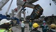 Recovery workers watch as a carriage of a train that crashed when a construction crane collapsed is lifted off the tracks in Thailand's Nakhon Ratchasima province on January 14, 2026. (Photo by Lillian Suwanrumpha / AFP)
 