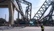 A recovery worker stands near the site of a construction crane collapse onto a highway in Samut Sakhon on the outskirts of Bangkok on January 15, 2026. (Photo by Chanakarn Laosarakham / AFP)