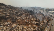 Aerial view of the charred remains of destroyed homes after a wildfire in Concepcion, Chile, on January 18, 2026. Chilean President Gabriel Boric declared a state of emergency on January 18 for two southern regions where raging wildfires have forced about 20,000 people to evacuate their homes. (Photo by Raul Bravo / AFP)

