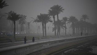 People dressed in winter clothes take a stroll as strong northwesterly winds brought temperatures down in Qatar yesterday.