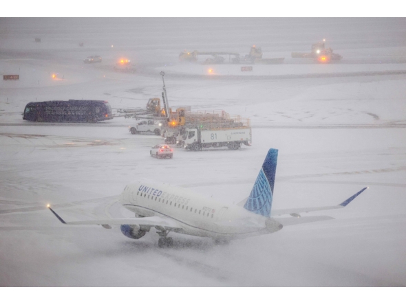 An Embraer 175 of United airlines taxies to take off as the snow falls on the tarmac of LaGuardia airport in New York on January 25, 2026. Photo by CHARLY TRIBALLEAU / AFP