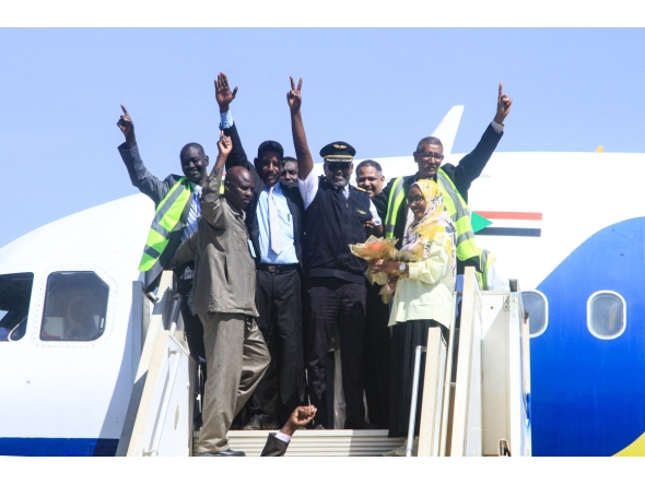 Sudan Airways members of staff celebrate as they stand at the door of the first domestic flight arriving from Port Sudan, after it landed at Khartoum International Airport following a three-year hiatus, on February 1, 2026. (Photo by Ebrahim Hamid / AFP)