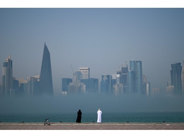 People look at the skyline covered in fog in Doha on February 9, 2026. (Photo by Mahmud HAMS / AFP)
