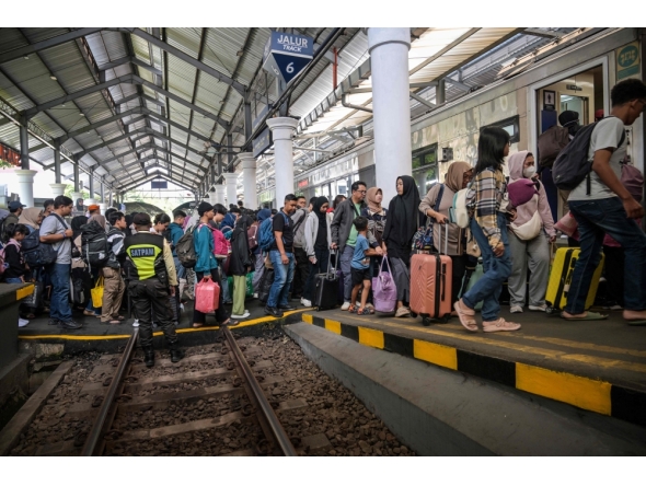 Passengers prepare to board a train to return home ahead of Eid al-Fitr, at Gubeng station in Surabaya on March 17, 2026. (Photo by Juni Kriswanto / AFP)