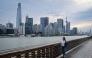 A woman walks along the Huangpu River as the city's skyline is seen in the background in Shanghai on April 9, 2026. (Photo by Jade Gao / AFP)