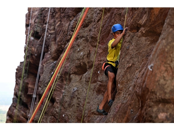 This photograph taken on March 28, 2026 shows a climber scaling a rock wall during a rock climbing festival at a sandstone cliffs site in Karnataka's Badami town. (Photo by Sajjad Hussain / AFP)