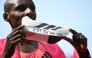 Kenya's Sabastian Sawe poses with his new world record time written on his running shoe at the finish of the 2026 London Marathon in central London on April 26, 2026. (Photo by JUSTIN TALLIS / AFP) / “Restricted to editorial use - sponsorship of content subject to LMEL agreement”.