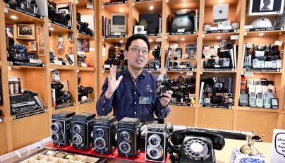 Takuya Kawai speaks while holding a camera. Photo credit: Japan News
