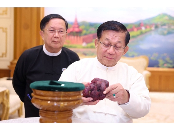 This handout photo taken and released on May 7, 2026 by Myanmar Radio and Television (MRTV) shows Myanmar president Min Aung Hlaing (R) holding an 11,000-carat ruby in Naypyidaw, after it was found at a gem tract in Mogok in Mandalay Region.  (Photo by Handout / Myanmar Radio and Television / AFP) /