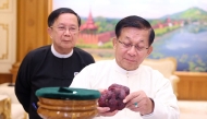 This handout photo taken and released on May 7, 2026 by Myanmar Radio and Television (MRTV) shows Myanmar president Min Aung Hlaing (R) holding an 11,000-carat ruby in Naypyidaw, after it was found at a gem tract in Mogok in Mandalay Region.  (Photo by Handout / Myanmar Radio and Television / AFP) /