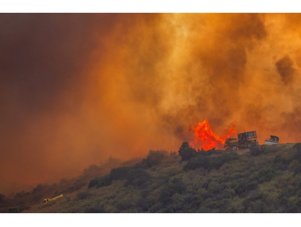 Fire fighters use a bulldozer to combat the Sandy Fire as it burns on a hill at a residential area in Simi Valley, California (Photo by Apu Gomes / AFP)