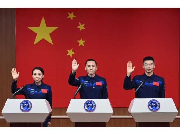 Astronauts for China's Shenzhou-23 space mission Lai Ka-ying (L), Zhu Yangzhu (C) and Zhang Zhiyuan (R) wave during a press conference before the launch of the mission at the Jiuquan Satellite Launch Center in the Gobi desert in Jiuquan, in northwestern China's Gansu province on May 23, 2026. (Photo by CNS / AFP)