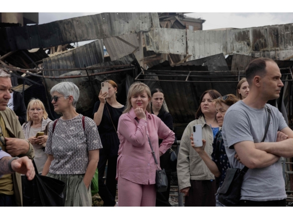 Local residents stand by a damaged shopping center following Russian strikes in Kyiv on May 25, 2026. (Photo by Tetiana Dzhafarova / AFP)