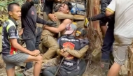This screen grab made from handout video footage taken on May 30, 2026, and provided by Adisak Wongsoraya, shows two men (centre L and centre R, with headlamp) being hugged after they were rescued from a semi-submerged cave in Laos' central Xaysomboun province, northeast of the capital Vientiane. Photo by Handout / Adisak Wongsoraya / AFP