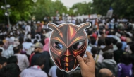 A Cockroach Janta Party (CJP) supporter holds a cockroach mask during a protest over alleged irregularities in the country's major examinations, in New Delhi on June 6, 2026. (Photo by Arun Sankar / AFP)