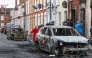 Residents and members of the media look at burnt-out cars and homes after demonstrations turned violent the night before, in eastern Belfast, Northern Ireland, on June 10, 2026. Photo by Paul Faith / AFP