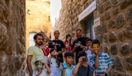 A group of children pose with their educators as they take pictures in the streets with film cameras during a workshop on June 14, 2026. (Photo by Yasin Akgul / AFP)