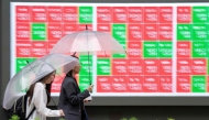 Pedestrians walk past an electronic quotation board displaying the Nikkei 225 stock prices on the Tokyo Stock Exchange along a street in Tokyo on June 25, 2026. (Photo by Kazuhiro NOGI / AFP)