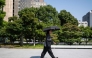 A man wearing all black walks through a park with an umbrella in Tokyo on July 22, 2026. (Photo by Andrew Caballero-Reynolds / AFP)