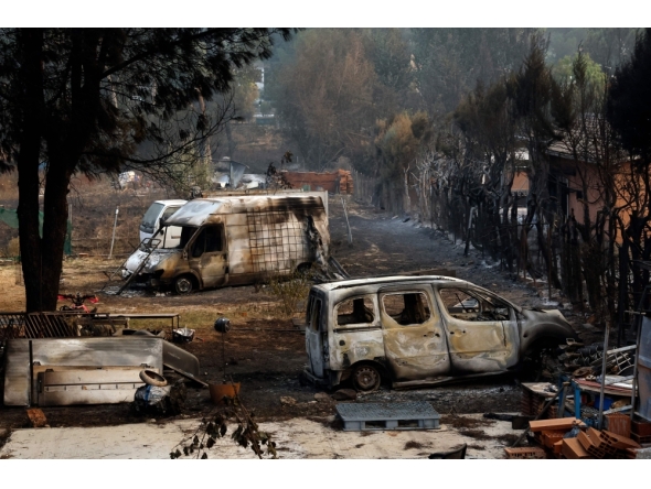 Burned cars sit in the yard of a home after a wildfire raged through Pelayos de la Presa, 65 kilometers west of Madrid, on July 26, 2026. (Photo by Oscar Del Pozo / AFP)