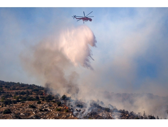 A firefighting helicopter drops water on a wildfire in Haidari, a suburb west of Athens, on July 31, 2026. (Photo by Aris Oikonomou / AFP)