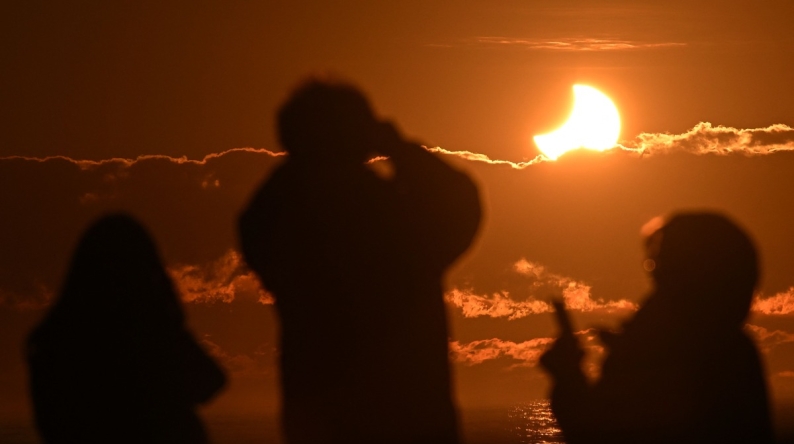 People watch a partial solar eclipse at New Brighton, a coastal suburb of Christchurch, on September 22, 2025. Photo by Sanka Vidanagama / AFP