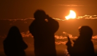 People watch a partial solar eclipse at New Brighton, a coastal suburb of Christchurch, on September 22, 2025. Photo by Sanka Vidanagama / AFP
