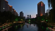 People paddle along the Liangma river at dusk in Beijing on August 5, 2026. (Photo by ADEK BERRY / AFP)