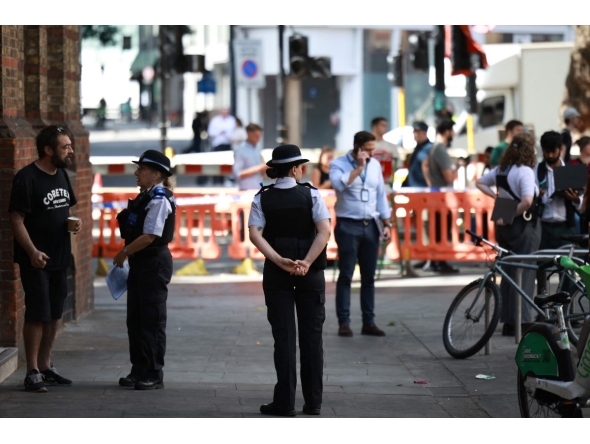 Police community support officers (PCSOs) stand behind cordon tape at Endell road in covent garden, central London on August 5, 2026. Photo by Henry NICHOLLS / AFP