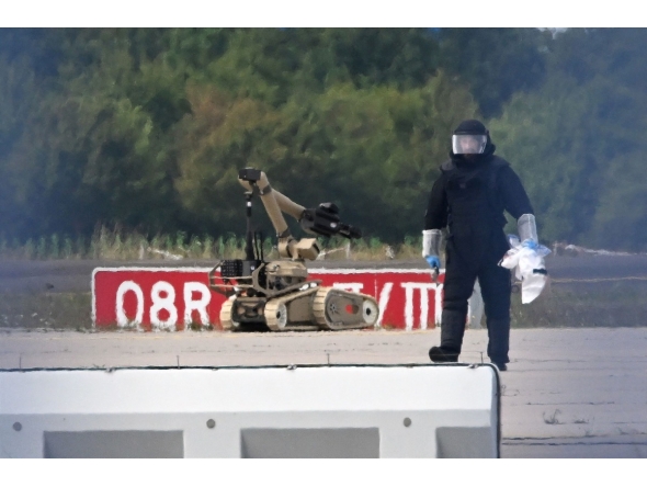 A forensic technician is at work alongside a bomb disposal robot near a Ukrainian cargo plane at Leipzig/Halle Airport in Schkeuditz, eastern Germany on August 5, 2026, after an explosives-laden drone was found near the plane overnight, and another aircraft collided with an unknown flying object mid-air nearby before landing safely. Photo by Hendrik Schmidt / dpa / AFP
