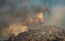 A firefighting helicopter drops water during a wildfire in the island of Salamina, near Athens, on August 16, 2026. (Photo by Yannis Panagopoulos / Eurokinissi / AFP)