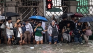 Commuters wade through a flooded street triggered by heavy monsoon rains in Manila on August 17, 2026. (Photo by Ted ALJIBE / AFP)
