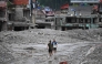 Flash flood survivors walk through sludge past damaged houses searching for salvageable belongings at Trishuli Center in Nepal's Nuwakot district on August 30, 2026. Photo by Arun SANKAR / AFP