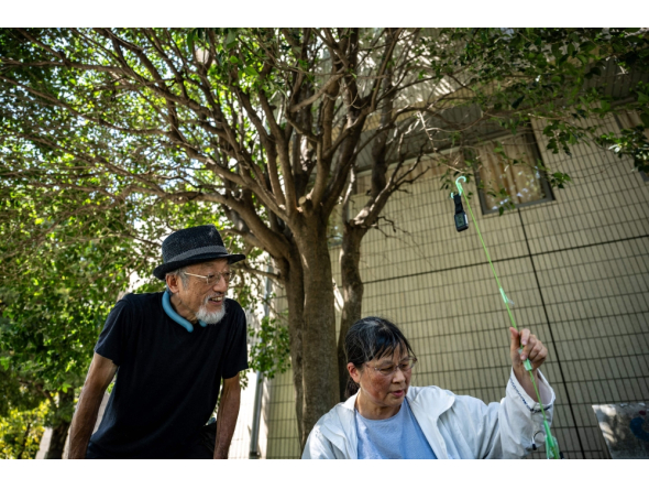 In this picture taken on August 25, 2026, activists Kaoru Morimoto (L) and Susumu Nirasawa check the temperature under a tree in the Nakano district of Tokyo. (Photo by Philip Fong / AFP)