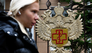 A woman walks past the logo of Russia's consumer and health watchdog Rospotrebnadzor sitting on its grounds' fencing in Moscow on October 5, 2026. Photo by Igor IVANKO / AFP