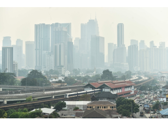 A dense layer of haze blankets the Kuala Lumpur skyline as a light rail train passes through the city on October 7, 2026.  (Photo by Arif Kartono / AFP)