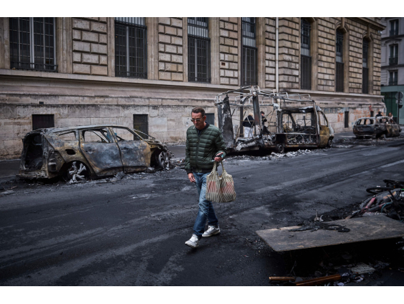 A man walks past a row of burnt out vehicles on Rue Yves Toudic destroyed after a nationwide protest against the 