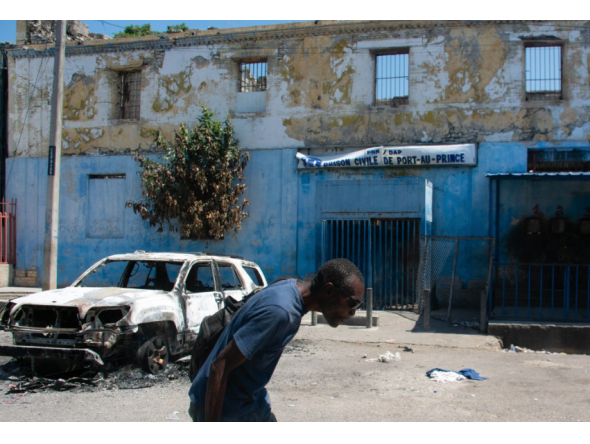 Man leaving prison area while lowering his head due to nearby gunfire in Port-au-Prince, Haiti. AFP file photo.