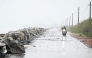 A scooterist rides along the Bay of Bengal coast during rainfall in Andhra Pradesh's Kakinada on October 27, 2026, ahead of cyclone Arnab's expected landfall. (Photo by Noah Seelam / AFP)
