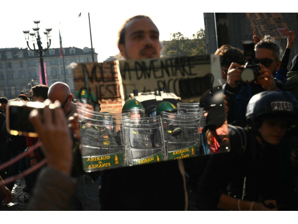 A protester holds a mirror to Guardia di Finanza officers during a demonstration part of a nationwide day of strikes and protests as school and university students demand more funding for schools and support for housing, in Turin on October 30, 2026. Photo by Marco BERTORELLO / AFP