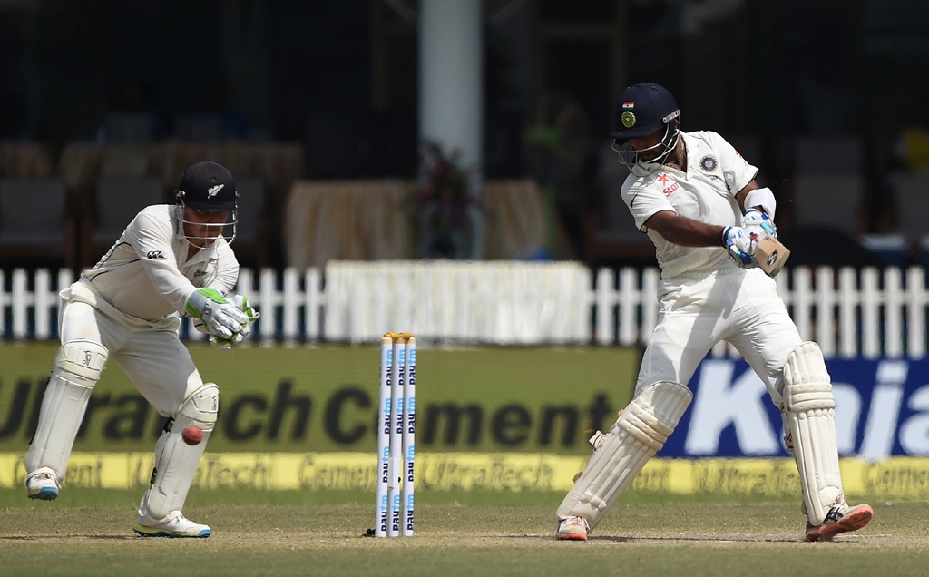 New Zealand's wicket keeper BJ Watling (L) watches as India's Cheteshwar Pujara plays a shot during the fourth day of the first Test match between India and New Zealand at Green Park Stadium in Kanpur on September 25, 2016. (AFP / PRAKASH SINGH)